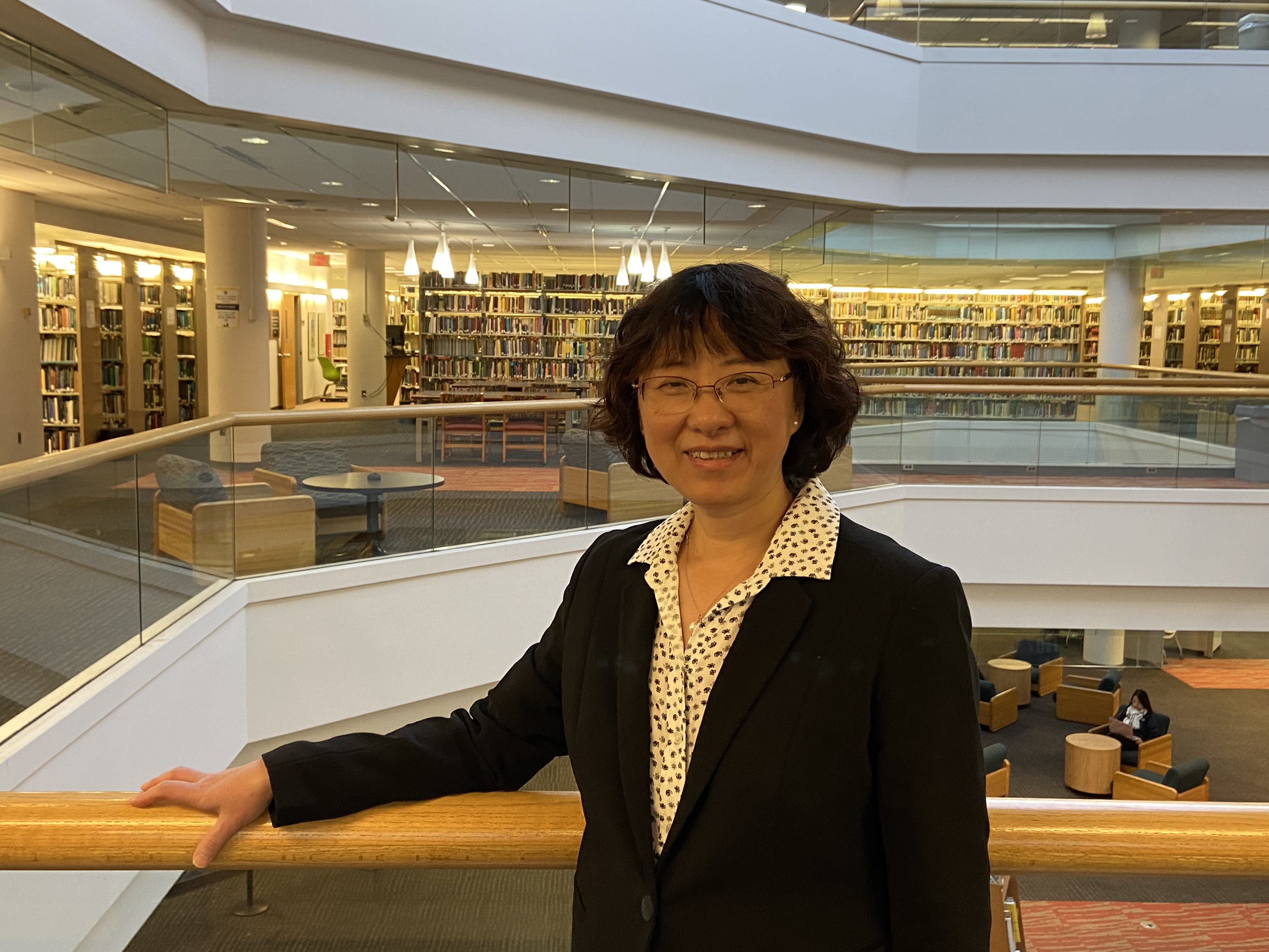 A woman stands against the railing on the 2nd floor of Hagerty Library